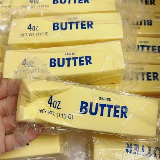 Multiple packages of 4oz salted butter with a hand holding one package.