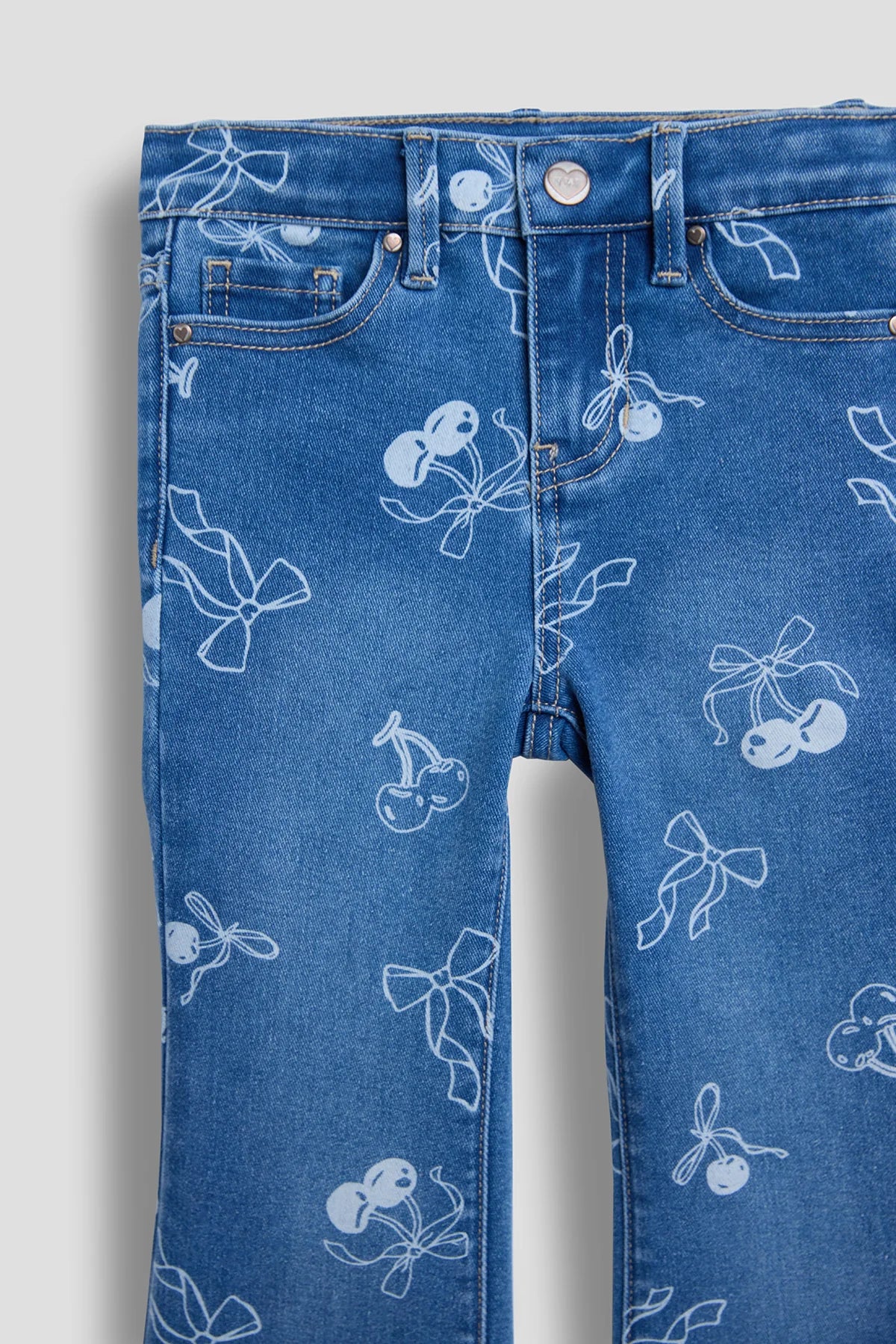 Blue jeans with white cherry and bow pattern on a white background
