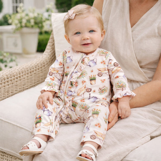 Baby in a floral outfit sitting on a couch with a blurred outdoor background