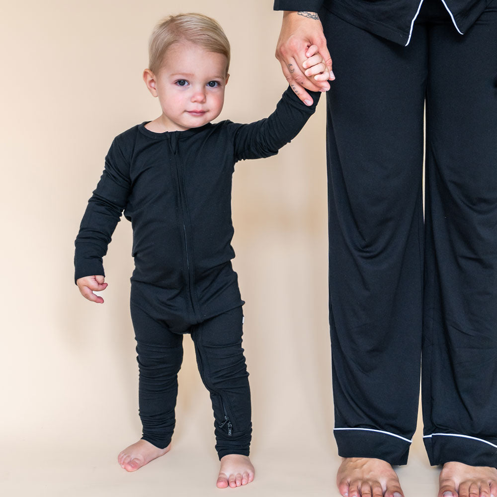 Child and adult wearingblack outfits on a beige background
