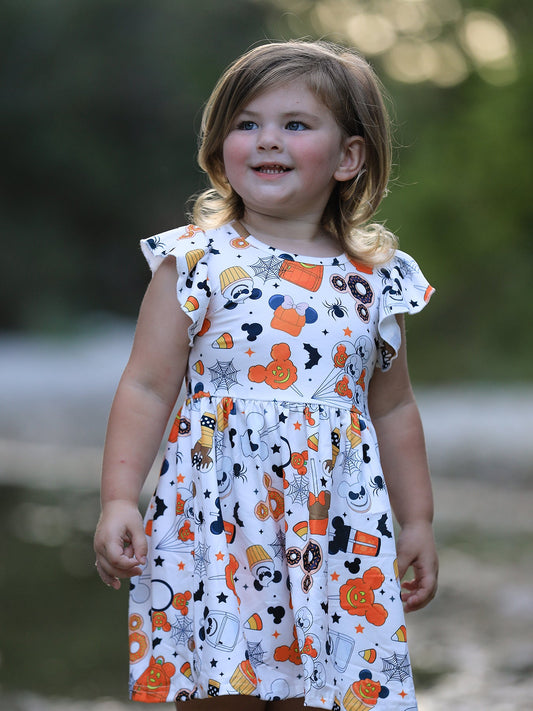 Young girl wearing a dress with Halloween-themed pattern outdoors