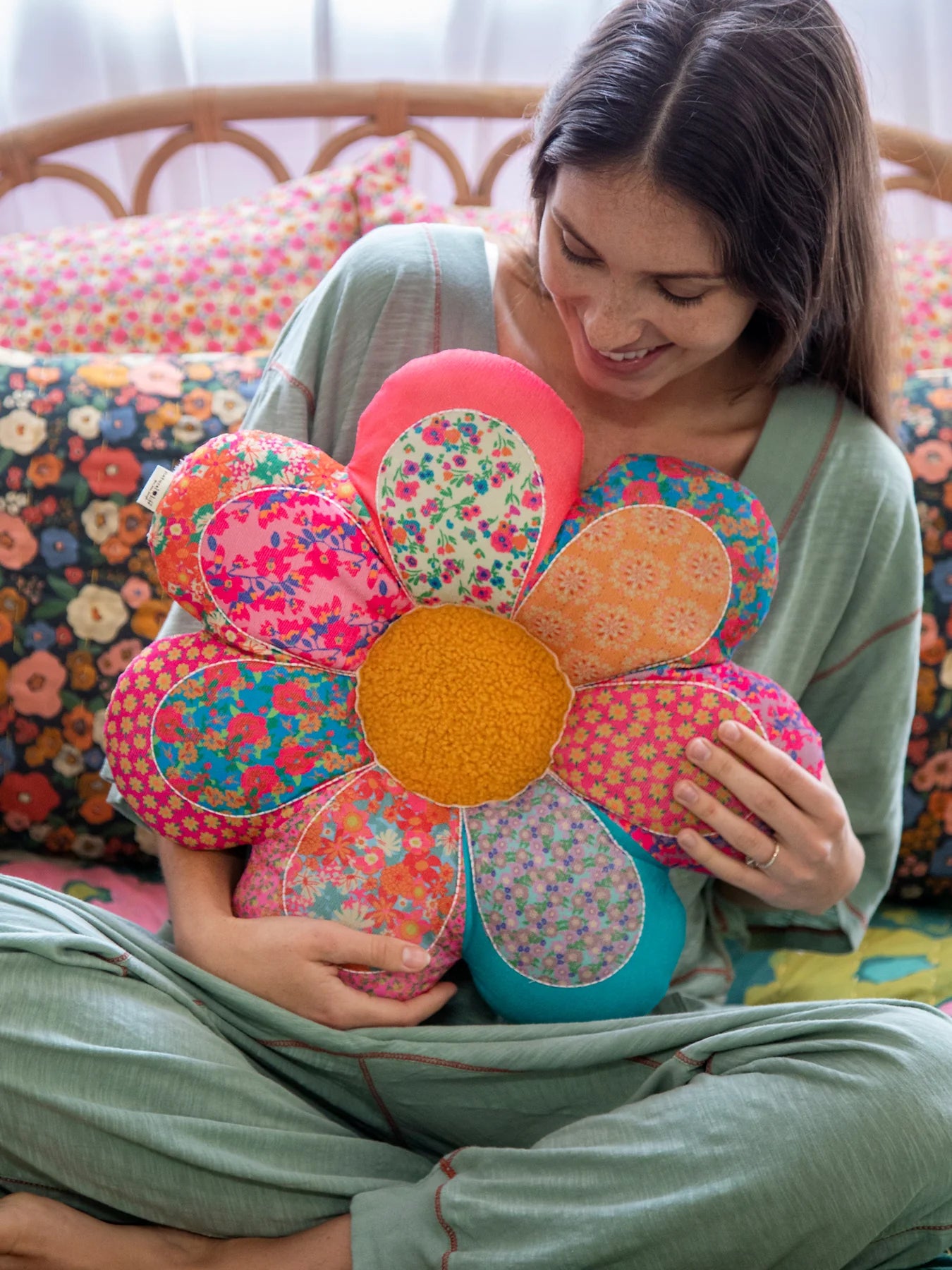 Woman holding a colorful flower-shaped pillow on a patterned couch