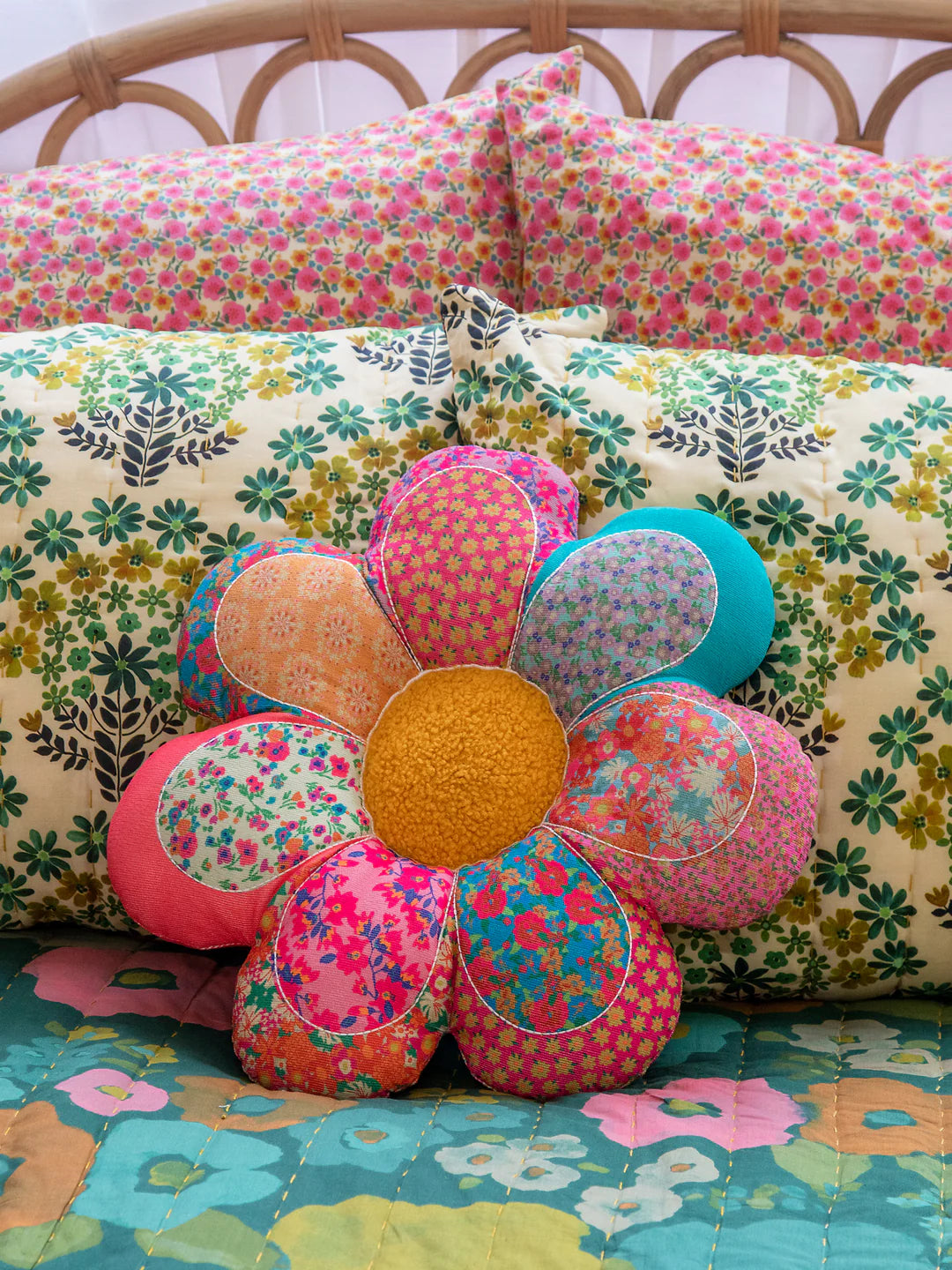 Floral-patterned pillow with a colorful flower design on a bed with floral bedding.