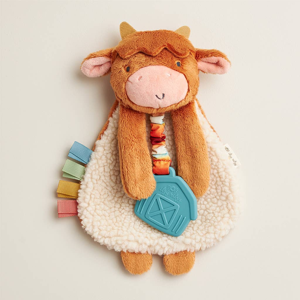 Plush cow toy with colorful elements on a light background