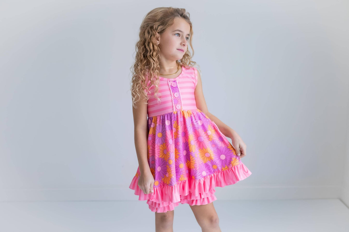 Young girl wearing a pink dress with floral pattern on a plain background