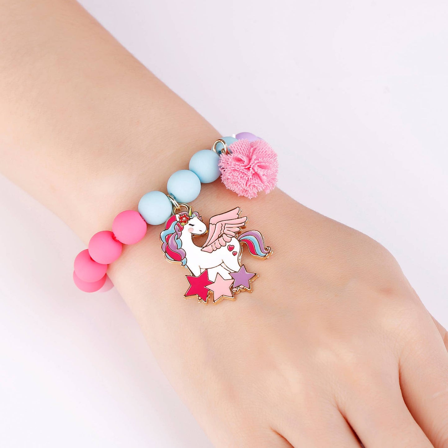 Colorful beaded bracelet with a unicorn charm on a wrist against a white background