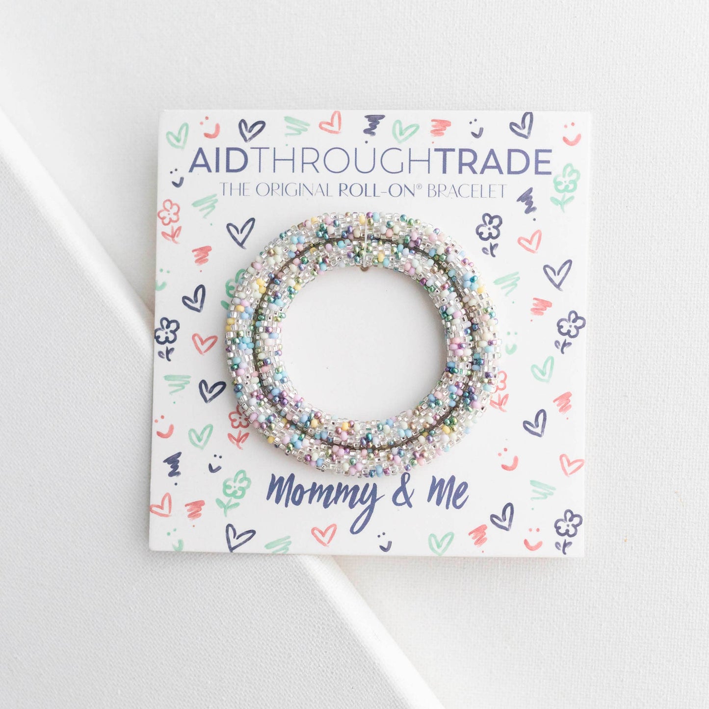 Bracelets on a 'Aid Through Trade' branded card with decorative patterns