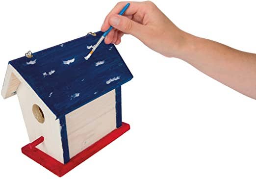 Hand painting a wooden birdhouse with blue paint on a white background