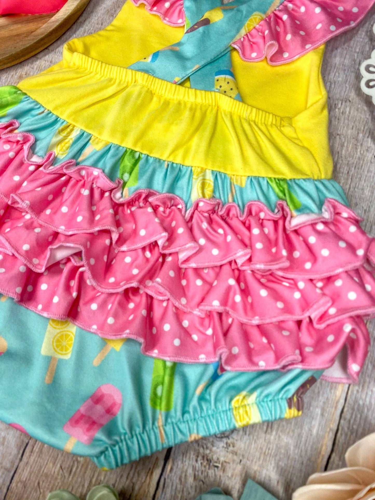 Colorful children's outfit with ruffled layers on a wooden surface