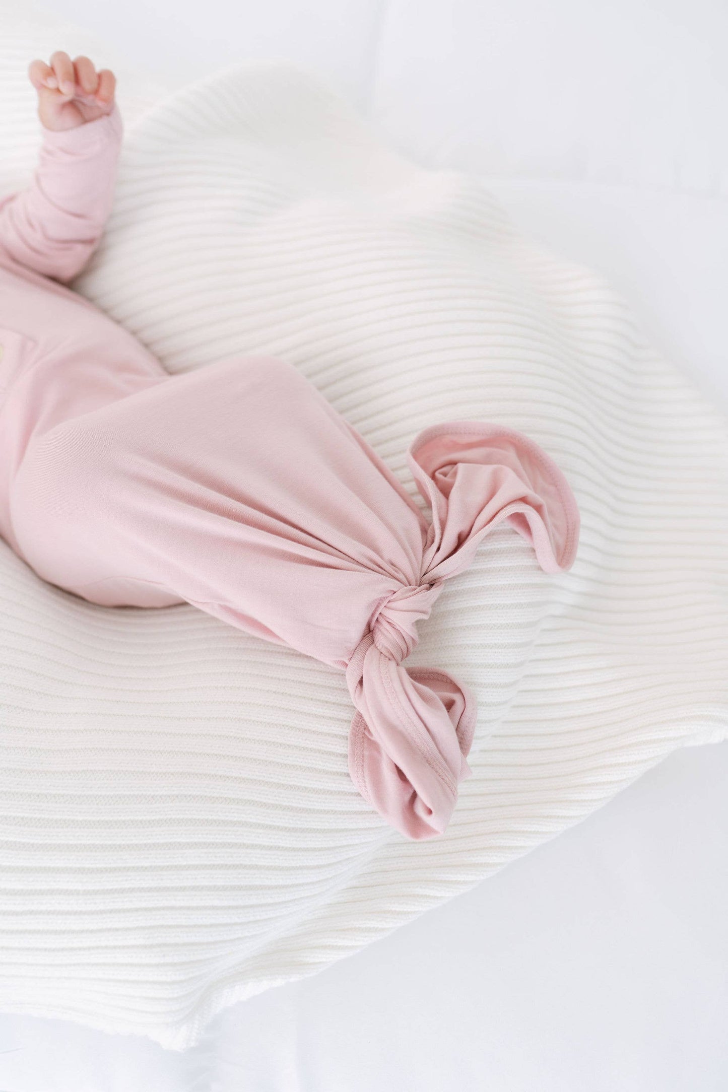 Baby in pink outfit lying on a white textured surface