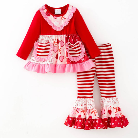 Children's outfit with red and pink top and striped pants on a white background