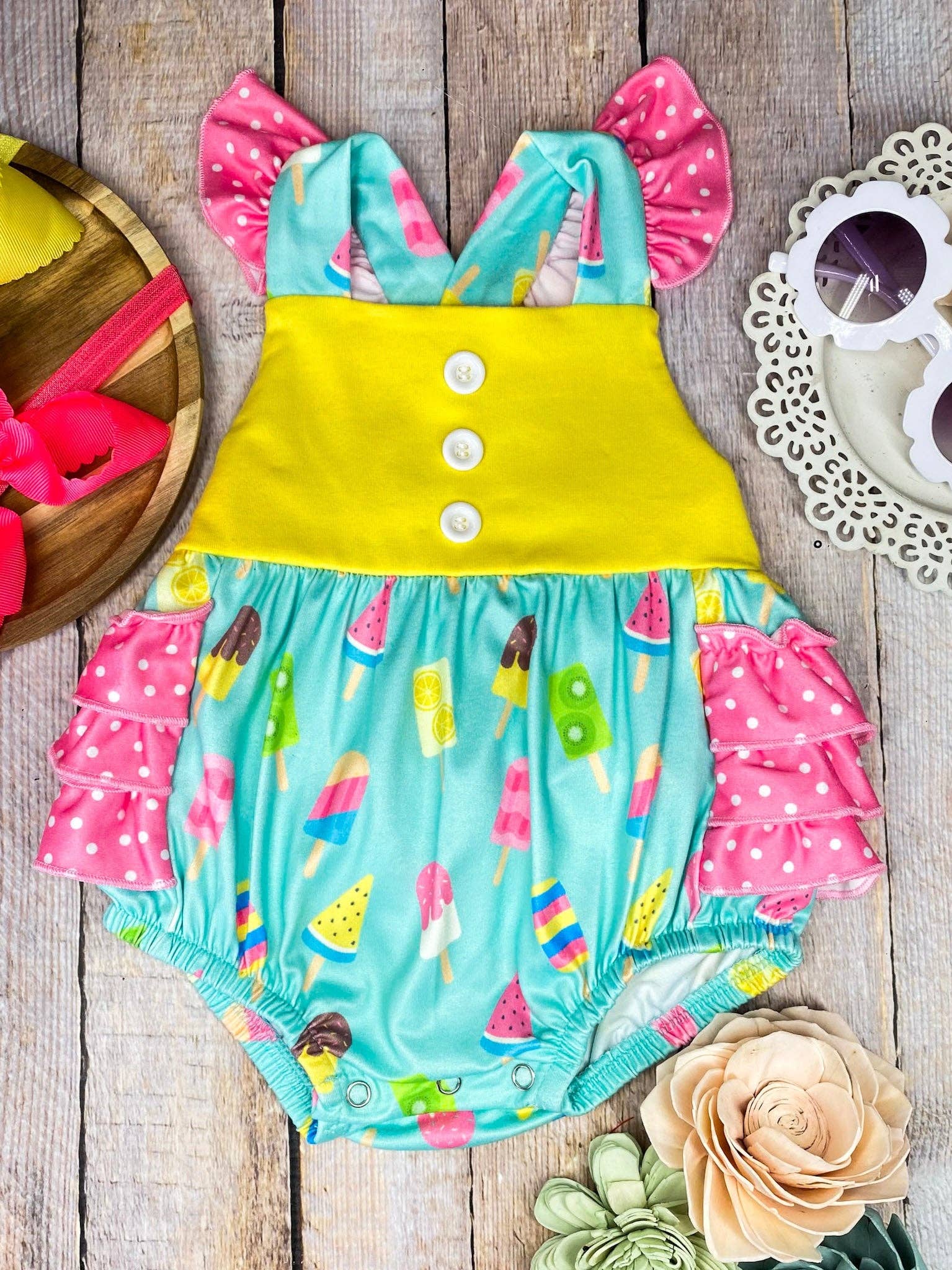 Colorful baby romper with ice cream pattern on a wooden surface