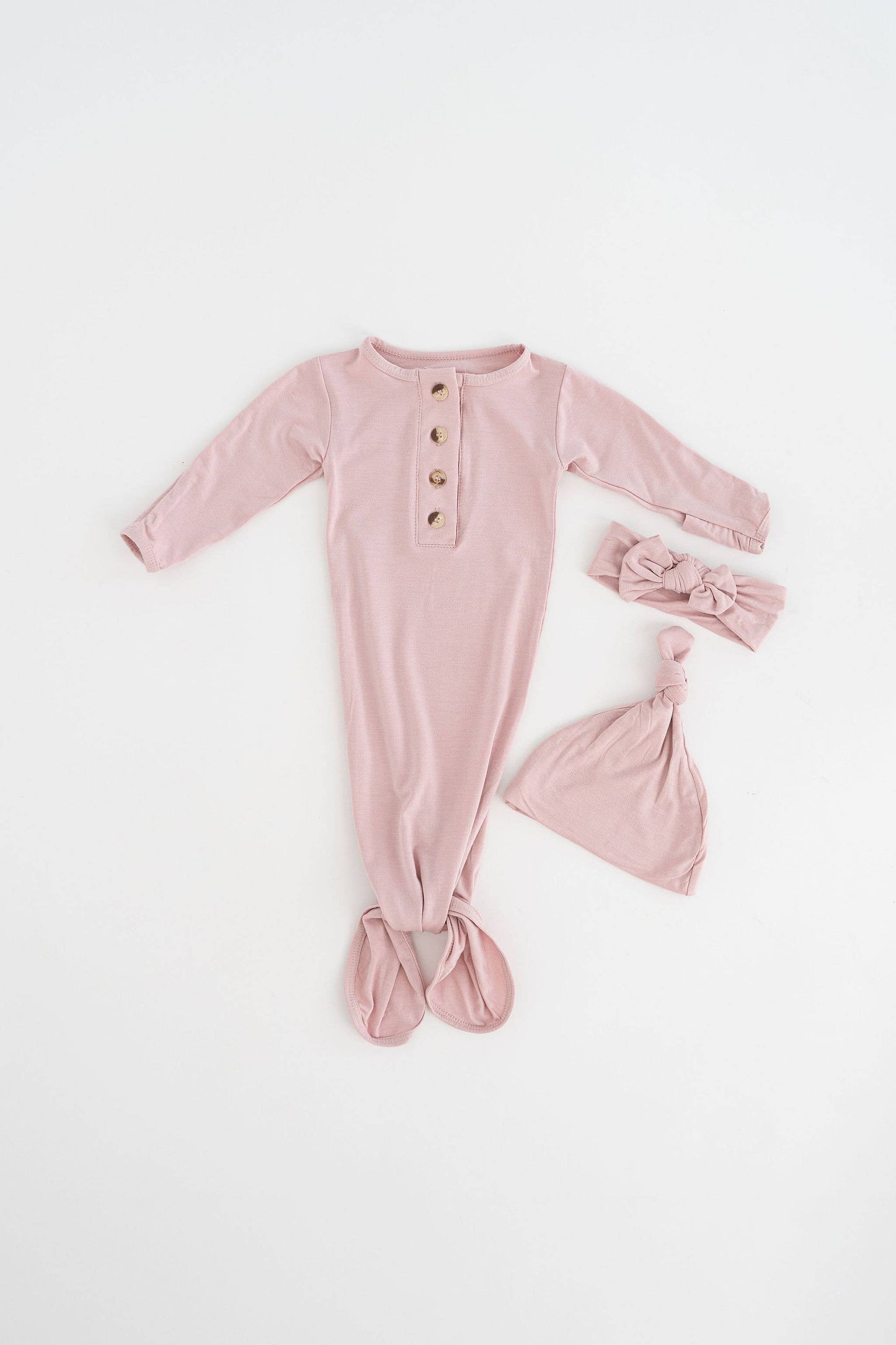 Pink baby onesie with buttons and matching headband on a white background