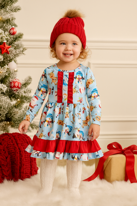 Child wearing a festive dress with reindeer pattern and red hat, standing next to a Christmas tree and gift.