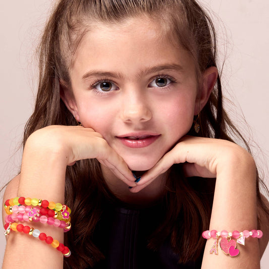 Young girl wearing colorful bracelets on a plain background