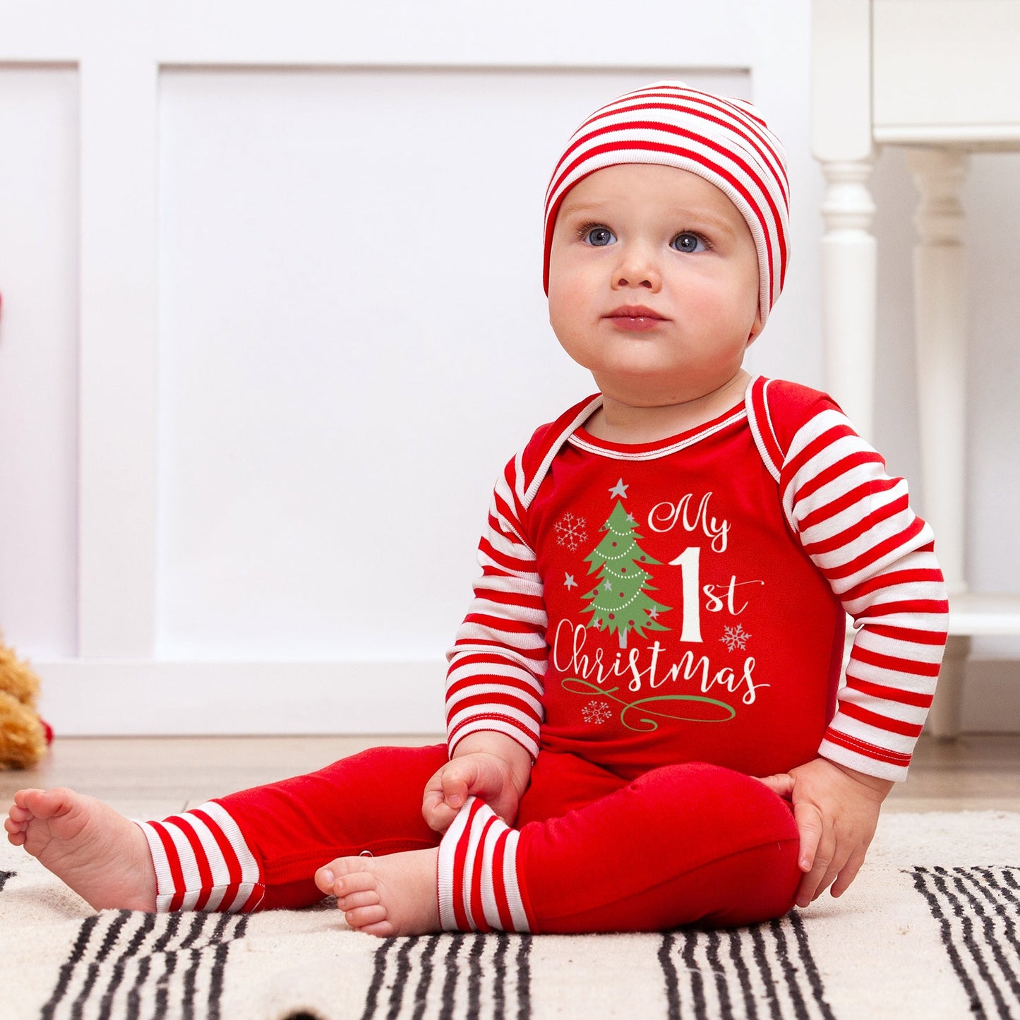 Baby wearing a red and white Christmas-themed outfit with a striped hat.