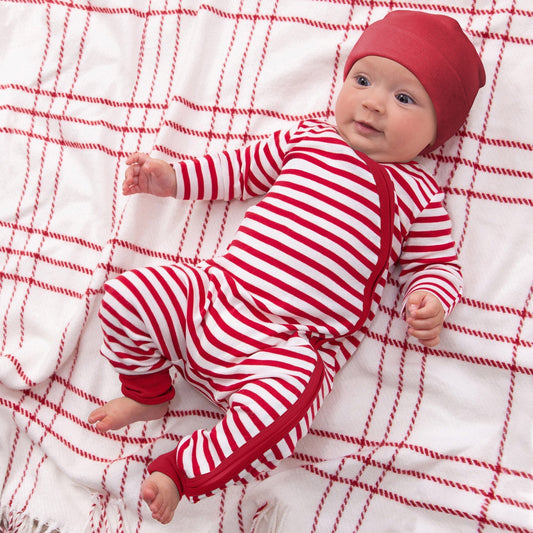 Baby in red and white striped outfit lying on a red and white checkered blanket